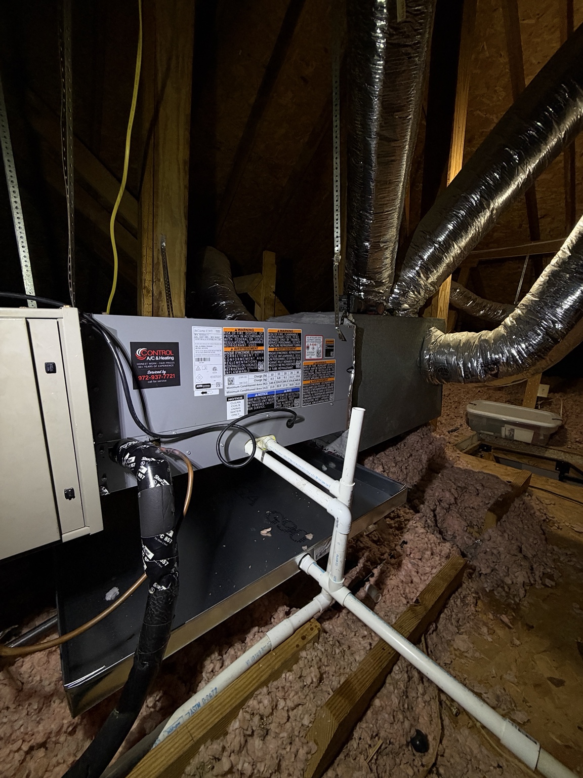 Attic air handler with Control A/C service sticker, insulated refrigerant line, and condensate drain