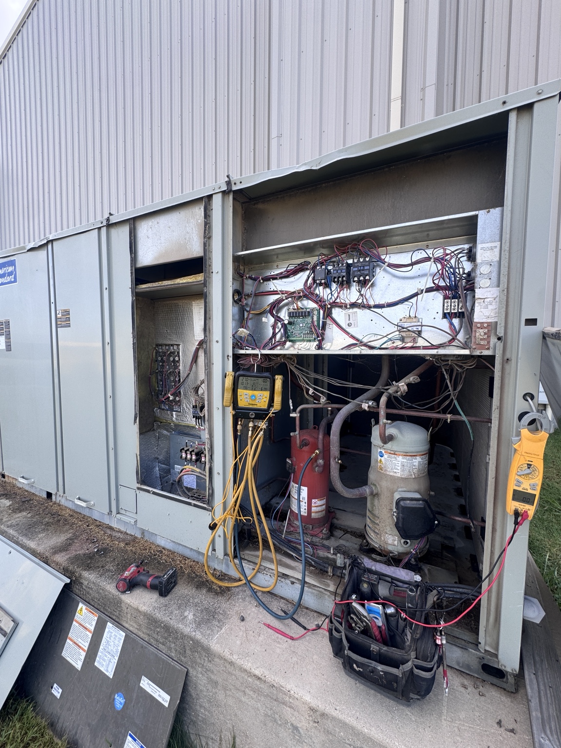 Commercial HVAC system being tested with refrigerant gauges and an electrical meter