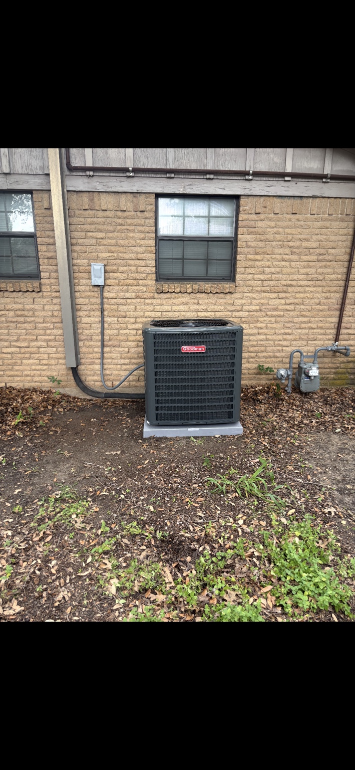 Goodman outdoor air conditioning unit installed beside a brick home